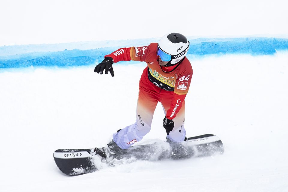 Ein Snowboarder in einem roten Trikot, mit weißem Helm und Brille fährt auf einer verschneiten Piste und wirbelt bei einer Kurve Pulverschnee auf. Eine blaue Linie markiert den Kurs auf dem Schnee neben ihnen.