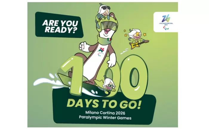 Ein fröhliches Cartoon-Maskottchen auf einem Snowboard mit zwei kleineren Figuren, umgeben von einem großen, fetten Text: NOCH 100 TAGE BIS ZUM START! Paralympische Winterspiele Mailand Cortina 2026. Das Logo erscheint in der oberen rechten Ecke.